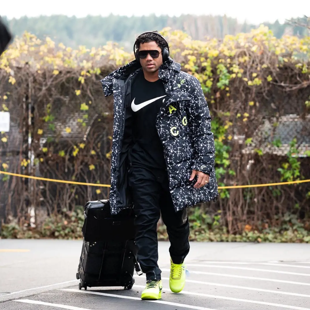 Russell Wilson shows off his massive Nike logo shirt as he checks into a motel in Seattle, Washington