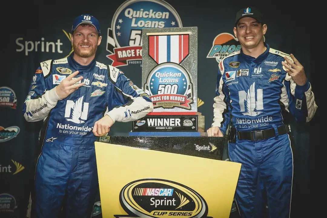 Dale Earnhardt Jr. (L) and Greg Ives pose in front of the Quicken Loans 500 trophy