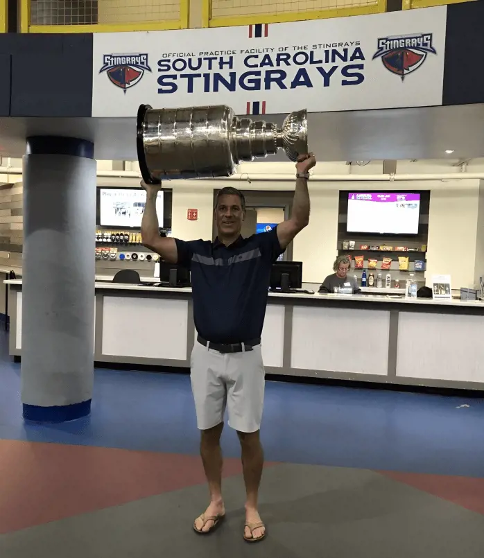 Bednar holding Stanley Cup infront of the South Carolina Stingrays board